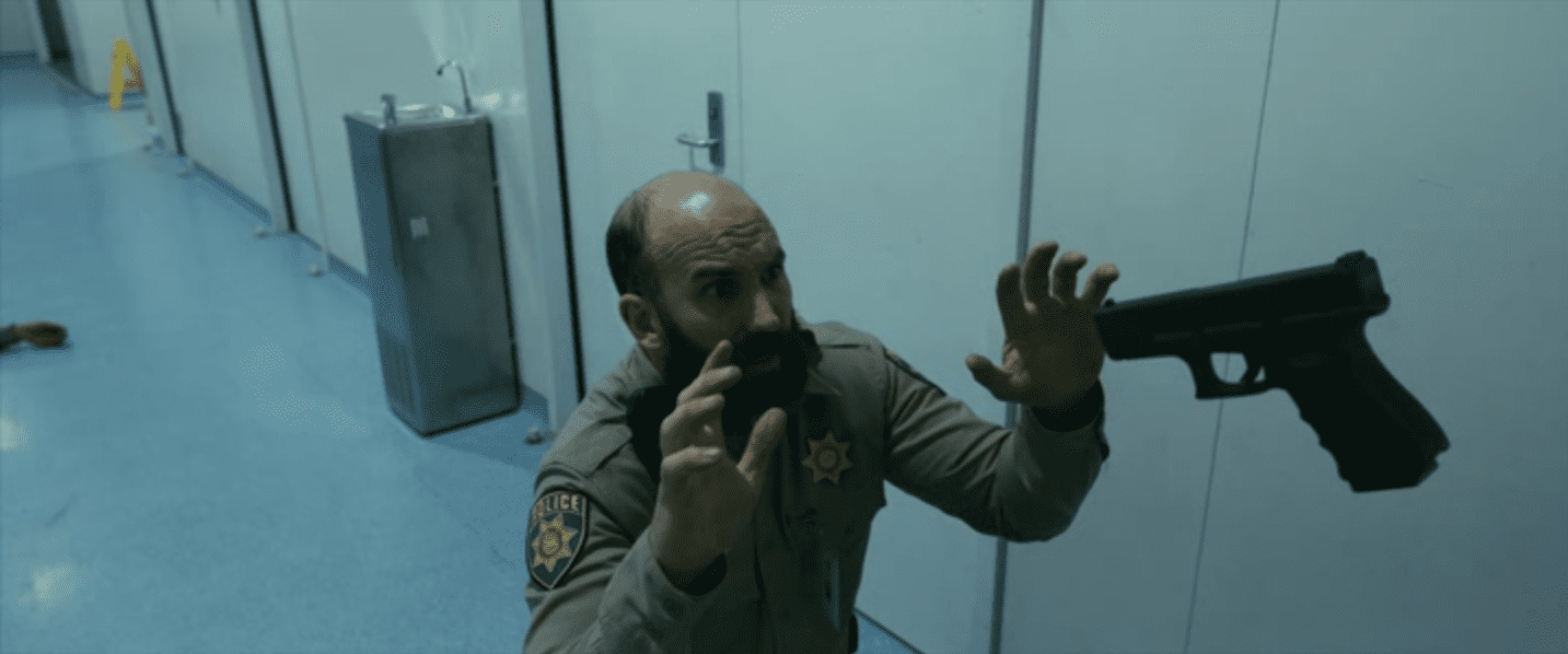 un policier tenu en joue par l'homme invisible