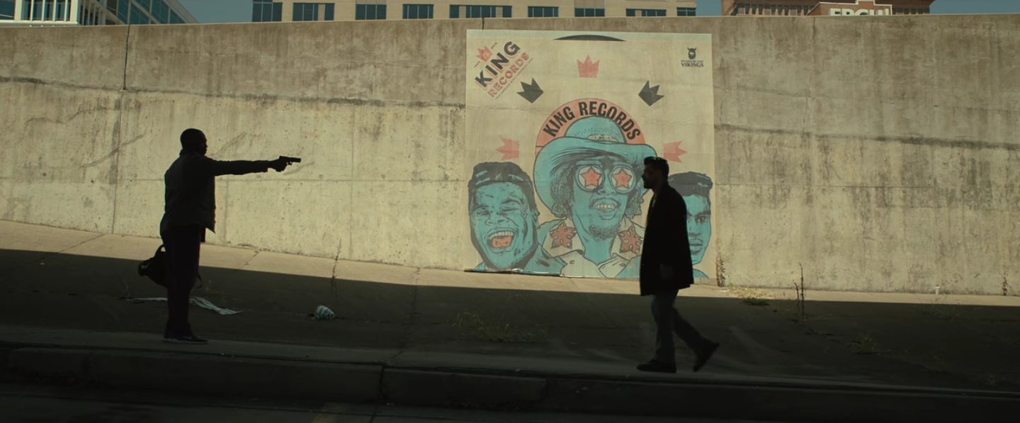 Scott Adkins tenant en joue ses adversaires dans un pub