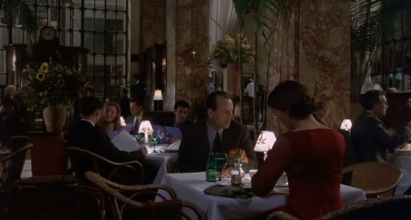 Malcolm vient de s'assoir à la table. Plan large.